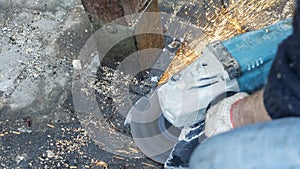 Close-up view of a worker working with angle grinder. Electric wheel grinding on steel structure. Sparks