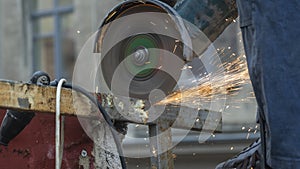 Close-up view of a worker working with angle grinder. Electric wheel grinding on steel structure. Sparks