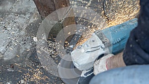 Close-up view of a worker working with angle grinder. Electric wheel grinding on steel structure. Sparks
