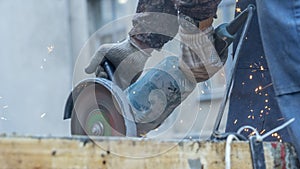 Close-up view of a worker working with angle grinder. Electric wheel grinding on steel structure. Sparks.