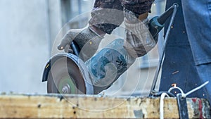 Close-up view of a worker working with angle grinder. Electric wheel grinding on steel structure. Sparks.