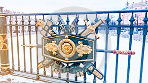 Close-up view of wrought military style ornament with arrows on metal rail. Golden sword and axe behind shield with coat