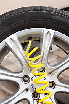 Close-up view at yellow hose of pneumatic pump connected to valve core. Inflating dismounted car wheel after repair blowout
