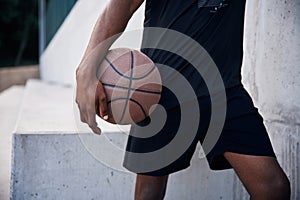 Close up view. Young black man is with basketball ball outdoors
