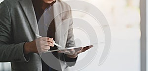 Close-up view of young businessmen working on his project while using tablet in modern office