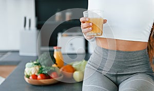 Close up view of young european woman that is indoors at kitchen indoors with healthy food and orange juice