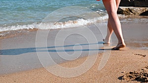 Close up view of young female legs on sandy shore. Close up view of female beautiful legs on sea. Close up of female legs walks on