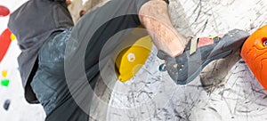 Close up view of young man or climber feet in climbing shoes on artificial indoor wall at climbing center, sport