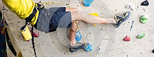 Close up view of young man or climber feet in climbing shoes on artificial indoor wall at the climbing center, sport