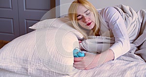 Close-up view of a young woman sleeps, wakes up, looks at the alarm clock and falls back to sleep.