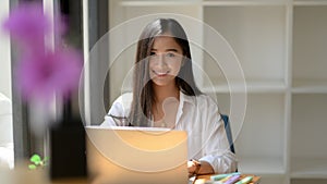 Close up view of young woman university student focusing on her work with laptop