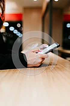 close up view of young woman using mobile phone in a cafe or restaurant indoors. Unrecognizable person lifestyles