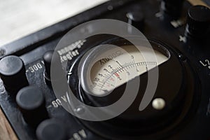 Close-up of vintage analog voltmeter with scale and control knobs