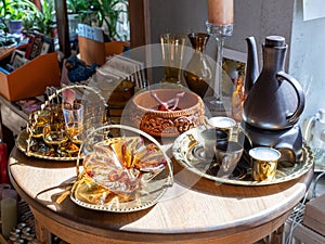 Close-up of vintage brown glassware on metal utensils. Carved bowl made of wood with a pattern. Wooden table. Sunlight.