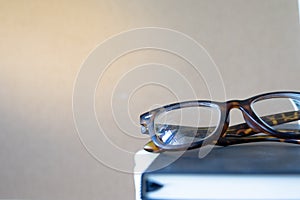 Close up vintage glasses on blurred black book stack with copy s