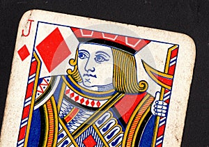 Close up of a vintage jack of diamonds playing card on a black background.