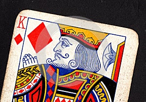 Close up of a vintage king of diamonds playing card on a black background.