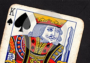 Close up of a vintage king of spades playing card on a black background.