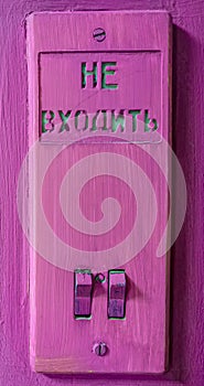 Close-up of a vintage light switch on a wall painted in purple.