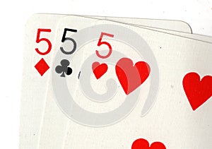Close up of vintage playing cards showing three fives.