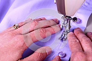 Close up of a vintage sewing machine and ladies hands guiding a cotton shirt