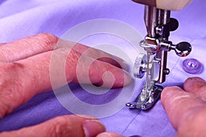 Close up of a vintage sewing machine and ladies hands guiding a cotton shirt