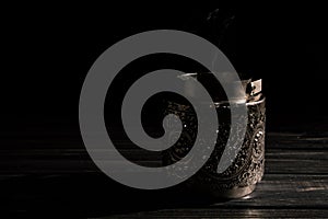 Close up. Vintage silver candlestick with extinguished candle, a trickle of gray smoke. Low key. Black background. Copy space