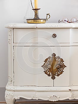 Close-up of vintage wooden bedside table with metal fitment. Candle and glasses for reading for cosy atmosphere. photo