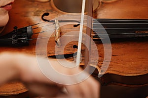 Close-up of a violin with a bow. Brown orchestra violin. Fingers on violin keyboard