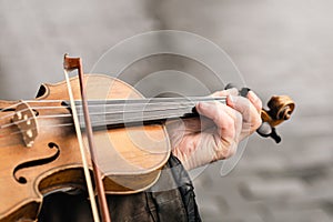 Close-up, a violin in the hands of an old man, a street musician.