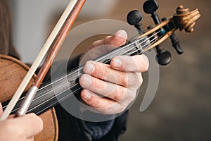 Close-up, a violin in the hands of an old man, a street musician.