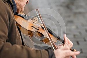 Close-up, a violin in the hands of an old man, a street musician.
