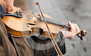 Close-up, a violin in the hands of an old man, a street musician.