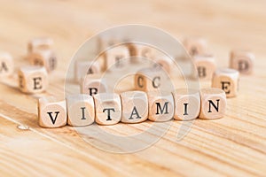 Close up vitamin word made from wooden letters on the table and A B C D E on the table background