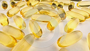 Close-up: vitamins and nutritional supplements in capsules on white background. Yellow and gold fish oil capsules are a