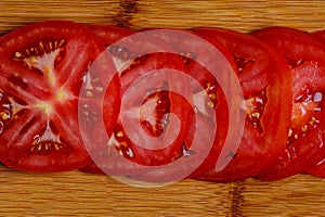A Close up vivd image of tomato slices on a bamboo cutting board