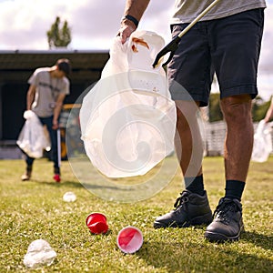 Close Up Of Volunteers Picking Up Litter After Outdoor Event Like Concert Or Music Festival