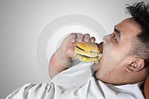 Voracious fat man eating a burger on studio