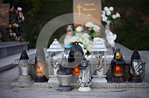 Close up of Votive candles lantern on the grave in Slovak Catholic cemetery during day. Autumn scene. All Hallows eve. Memorial