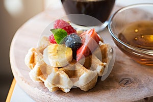 Close up of waffles with berries and honey on a wooden board