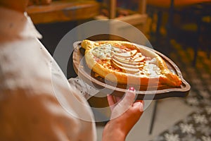 Close up of waiter serving a plate of Khachapuri - hachapuri in Adjarian. Waiter at work. Restaurant service.