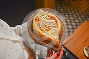 Close up of waiter serving a plate of Khachapuri - hachapuri in Adjarian. Waiter at work. Restaurant service.