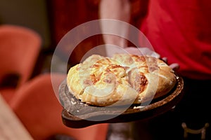 Close up of waiter serving a plate of Khachapuri - hachapuri in Adjarian. Waiter at work. Restaurant service.