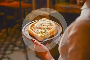 Close up of waiter serving a plate of Khachapuri - hachapuri in Adjarian. Waiter at work. Restaurant service.