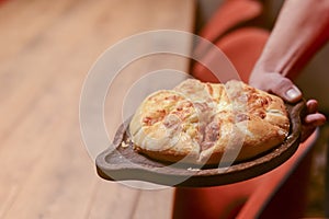 Close up of waiter serving a plate of Khachapuri - hachapuri in Adjarian. Waiter at work. Restaurant service.