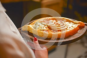 Close up of waiter serving a plate of Khachapuri - hachapuri in Adjarian. Waiter at work. Restaurant service