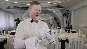 A close-up of a waiter in white gloves with a bottle of wine in a restaurant.