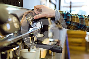Waitress making coffee using a professional coffee in a coffee shop.