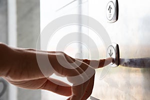 Close up woman hand press a down button of elevator