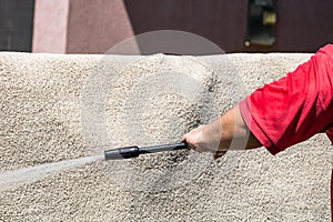 Close up of washing carpets with high pressure washer. Cleaning the carpet with a gun for washing high pressure water. House